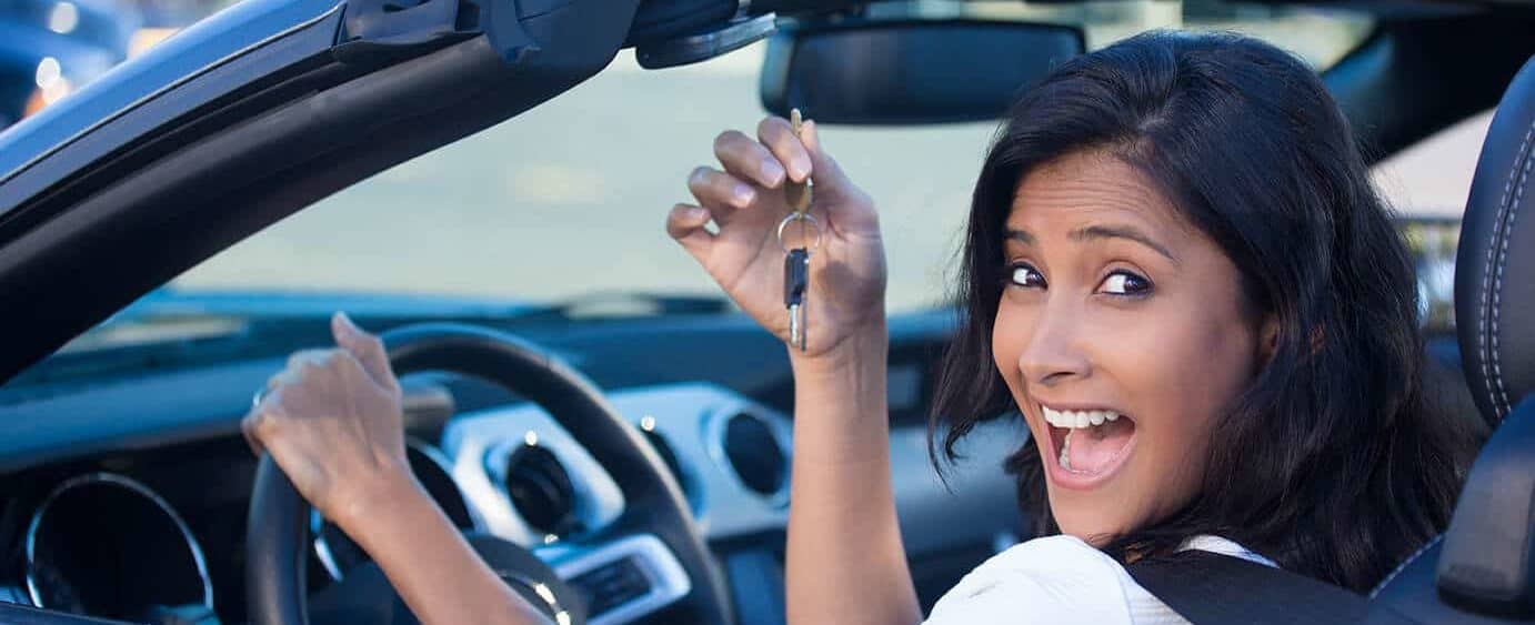 Happy woman in a brand new car holding her keys.